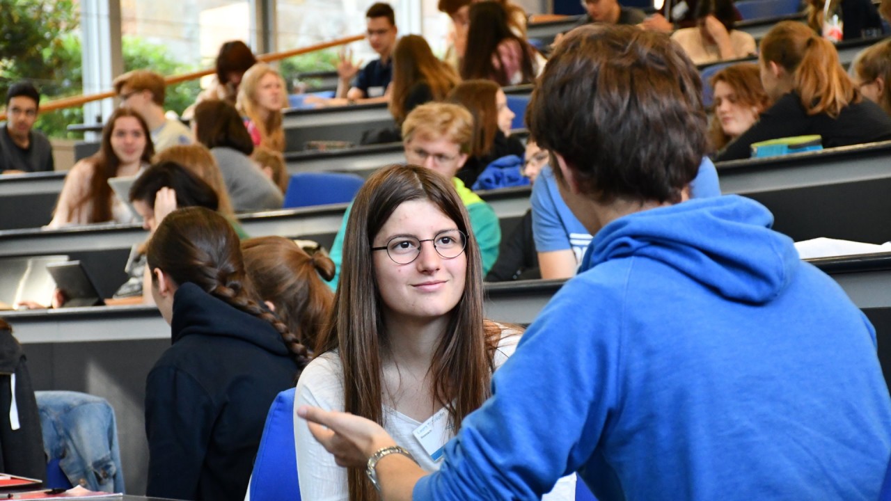 Students conversating in an auditorium. 