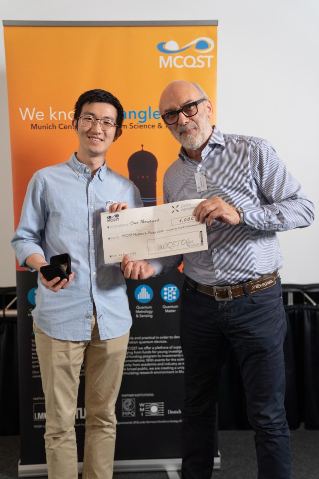 Thesis supervisor and student standing alongside each other showcasing the holding the award check at the MCQST2023 conference.