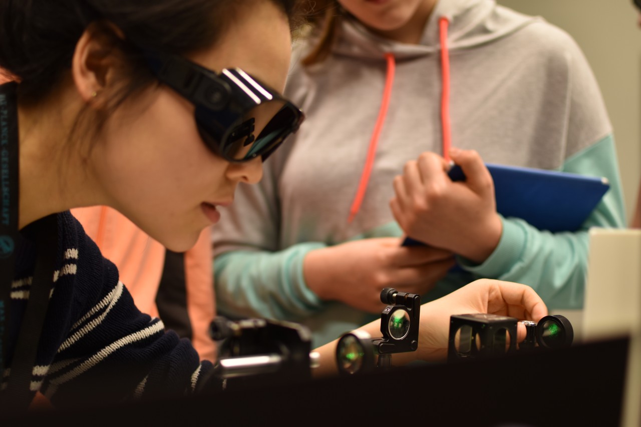 Close-up of female scientist fine tunning a laser table top. 