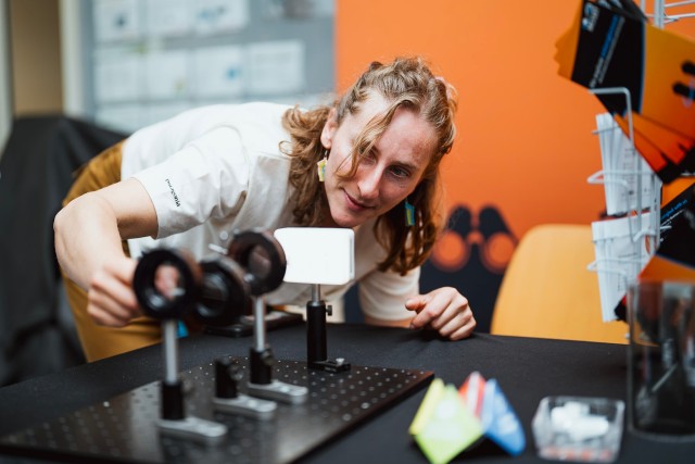 Female researcher adjusting the polarising filter of a demo set-up.