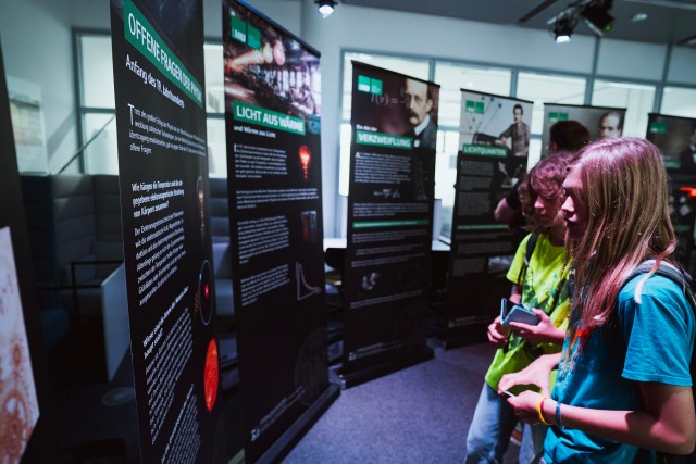 Two kids reading from the roll-ups of the exhibition.