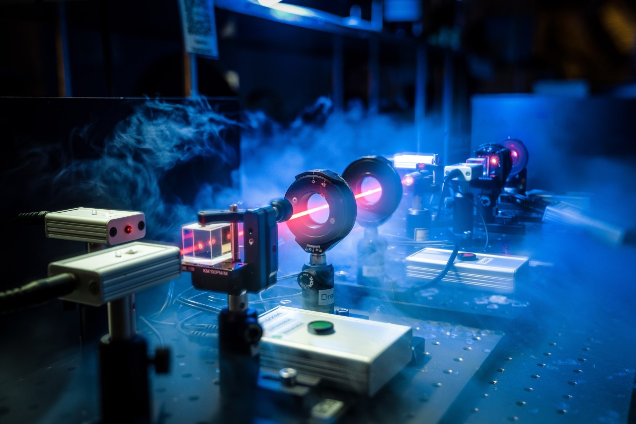 Close up of a red laser beam going through optical lenses in an quantum cryptography experiment.