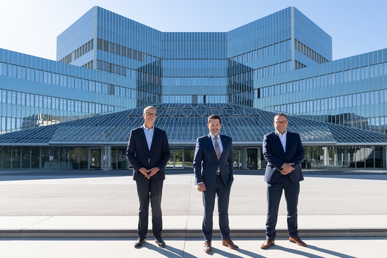 Photo featuring BMW AG Board of Management member Frank Weber, TUM president Thomas F. Hofmann, BMW AG CIO Alexander Bureschin front of a big modern glass building.