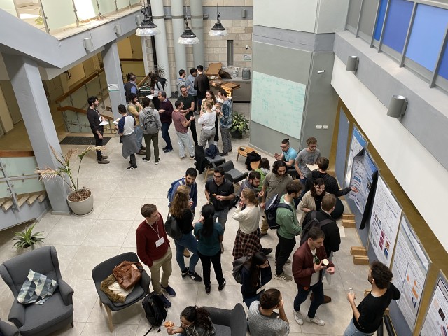 Group of people standing and discussing in front of scientific posters. 