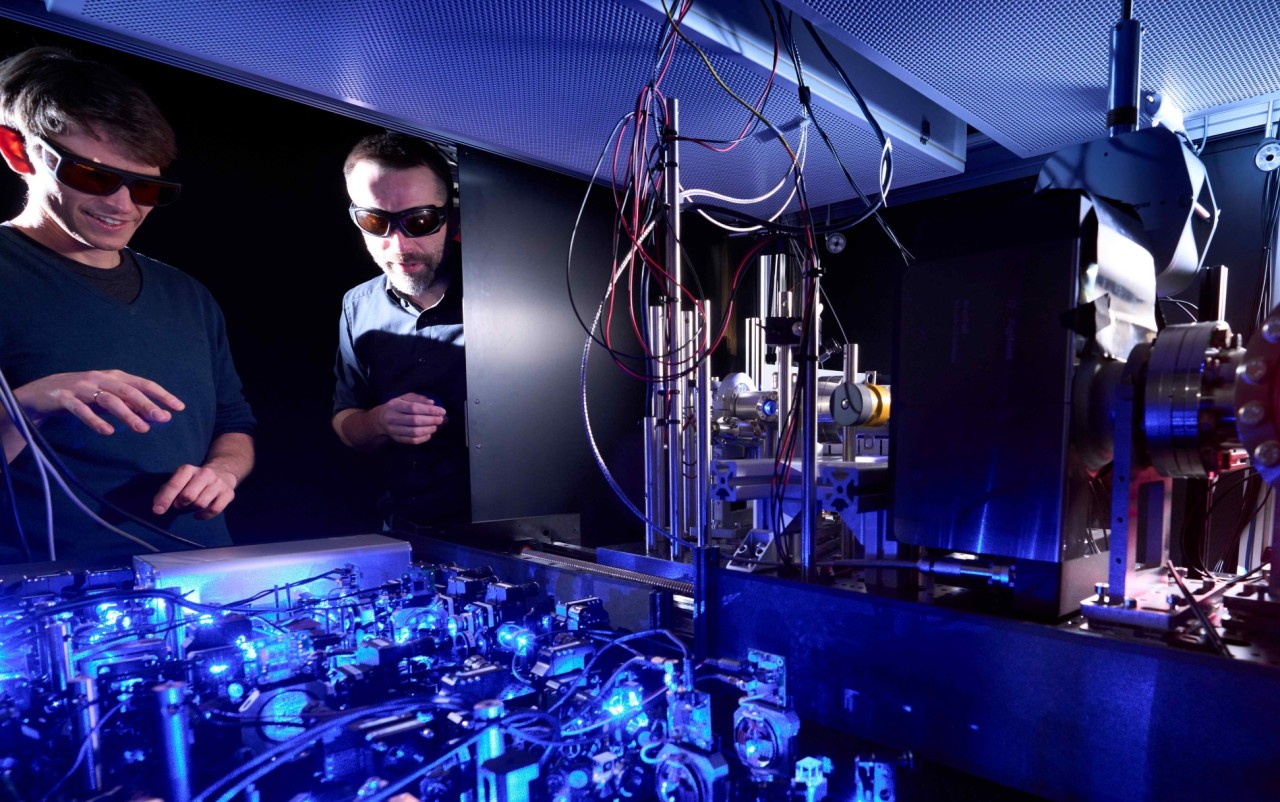 Analog quantum simulator Prof. Johannes Zeiher (left) in the laboratory with typical setups for a quantum simulation experiment,