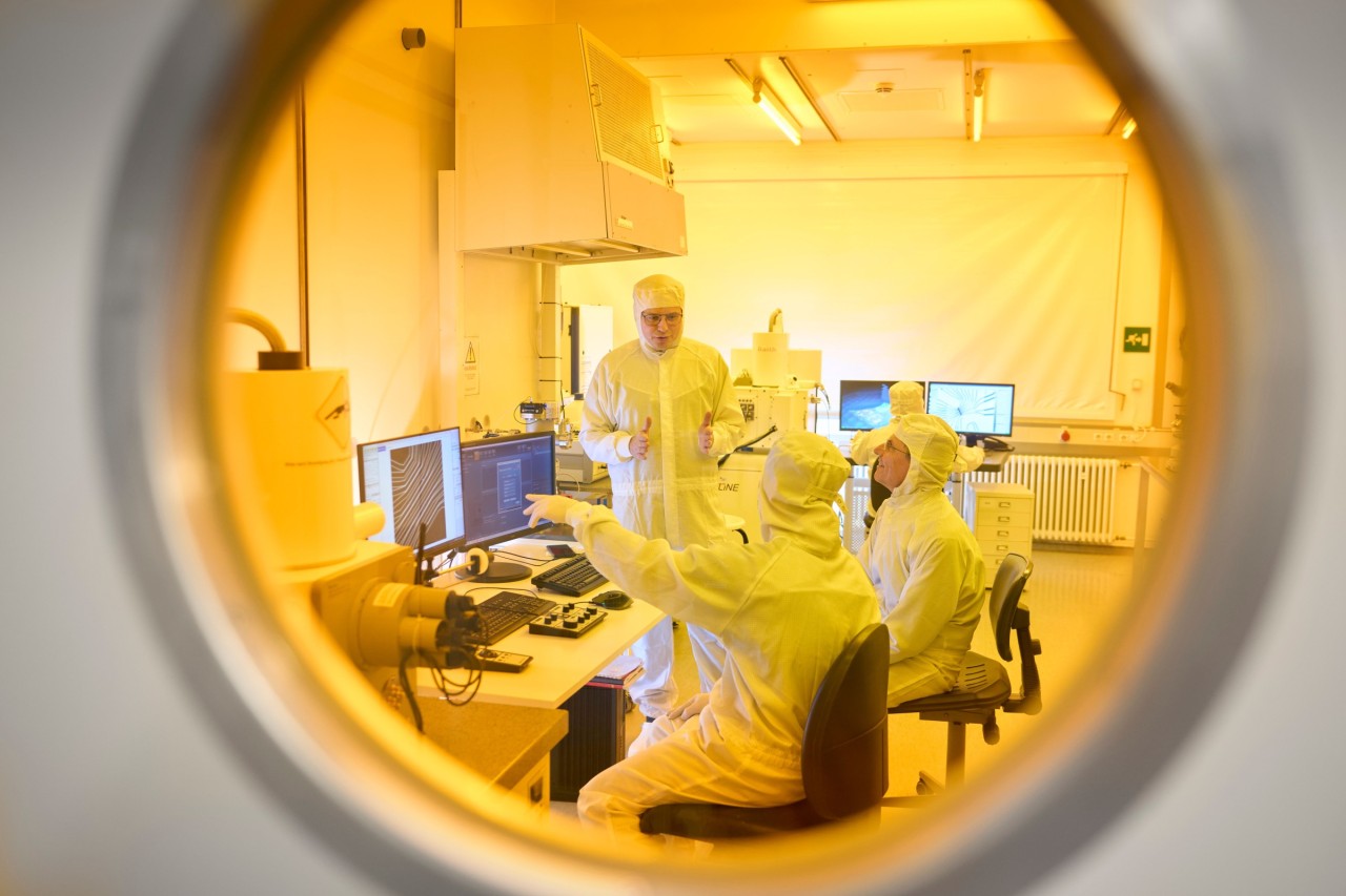 Scientists dressed in clean room suits analyzing the behavior of two-layered graphene.