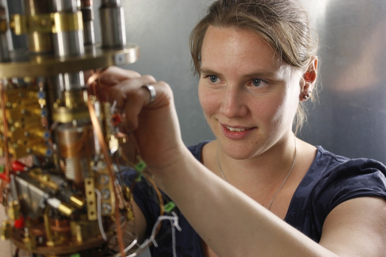 Female scientist working on an opened cryostat.