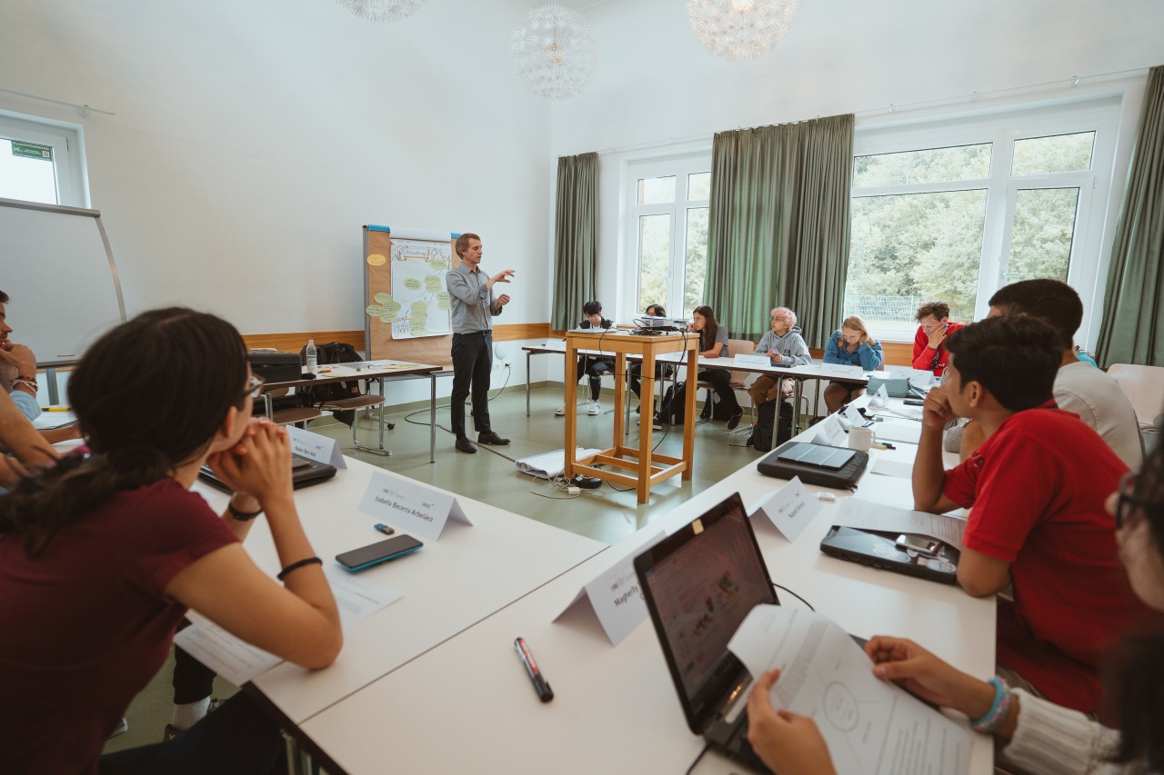 Students sitting in a seminar room listenin to the workshop trainer, who is standing in front and presenting. 